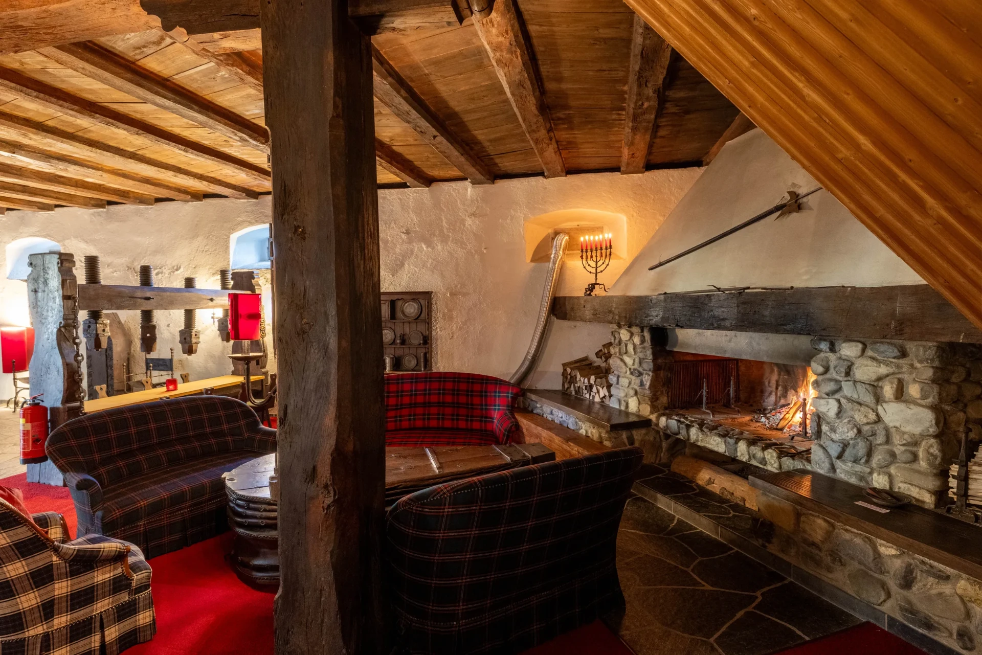 Event-Keller: Kaminlounge mit historischem Weinpressen-Balken und Steinwänden