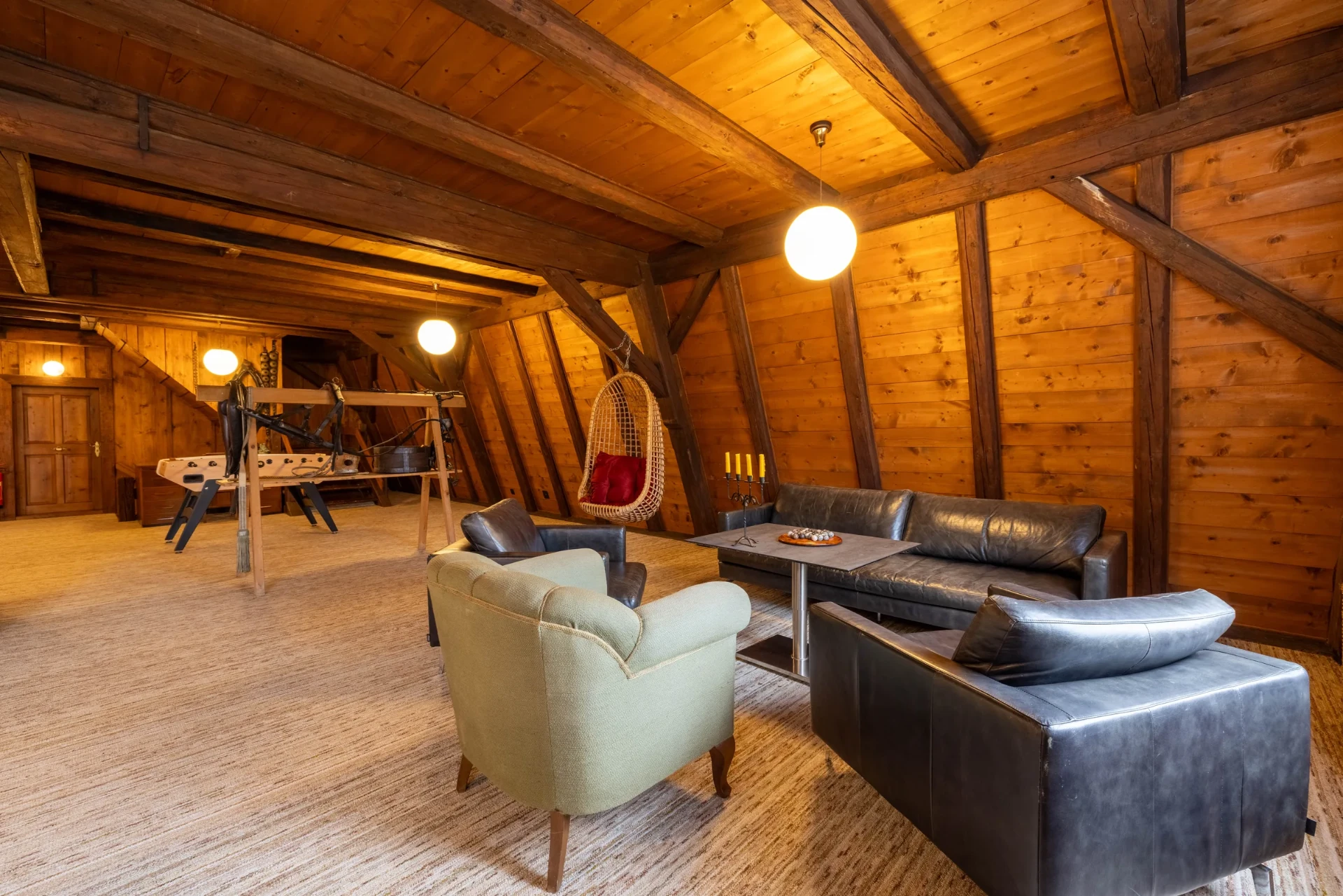 Lounge-Bereich mit Ledersofas, alter Wippe und historischen Holzbalken