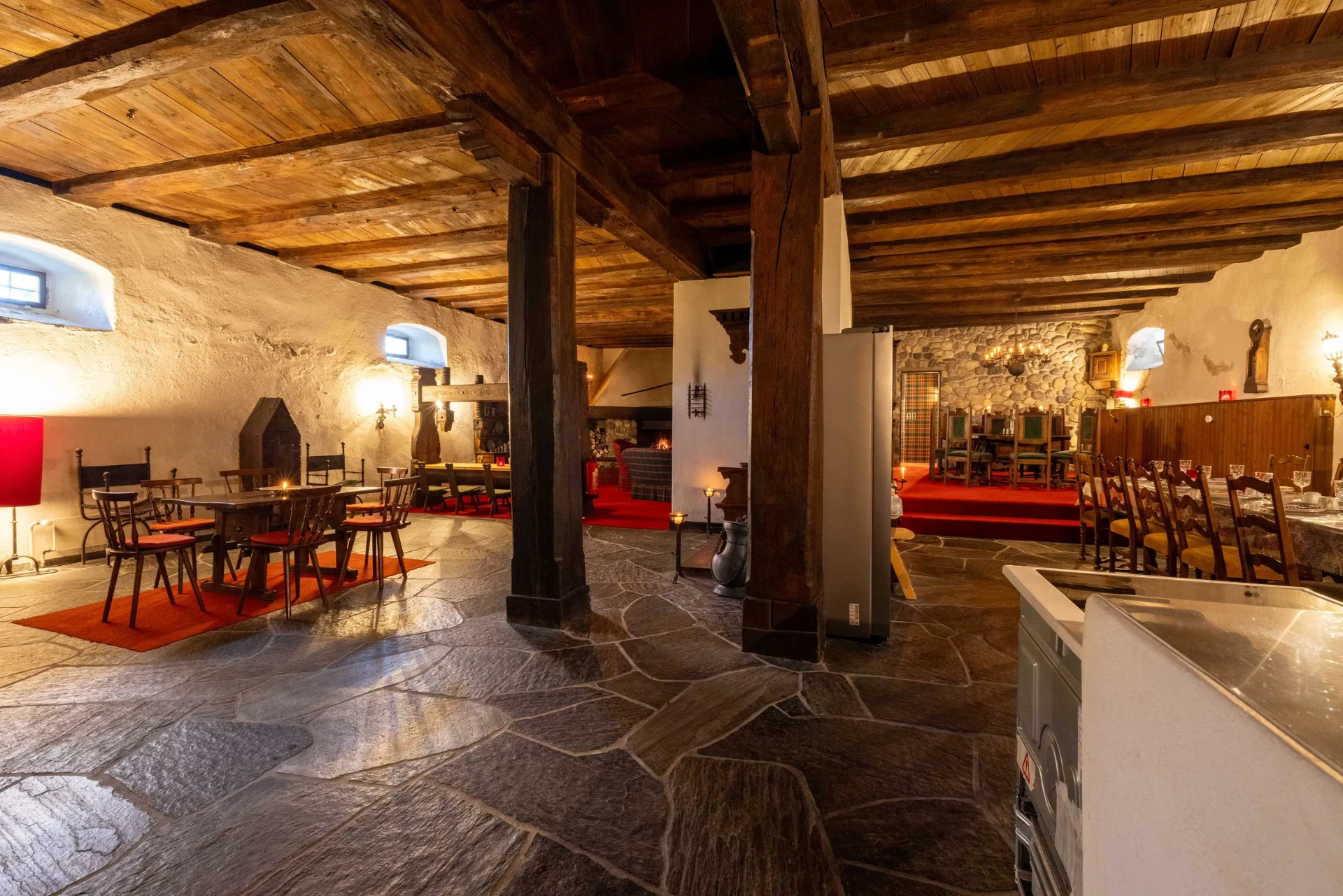 Event-Keller: Raumübersicht mit Natursteinboden, Tischen und Kaminlounge