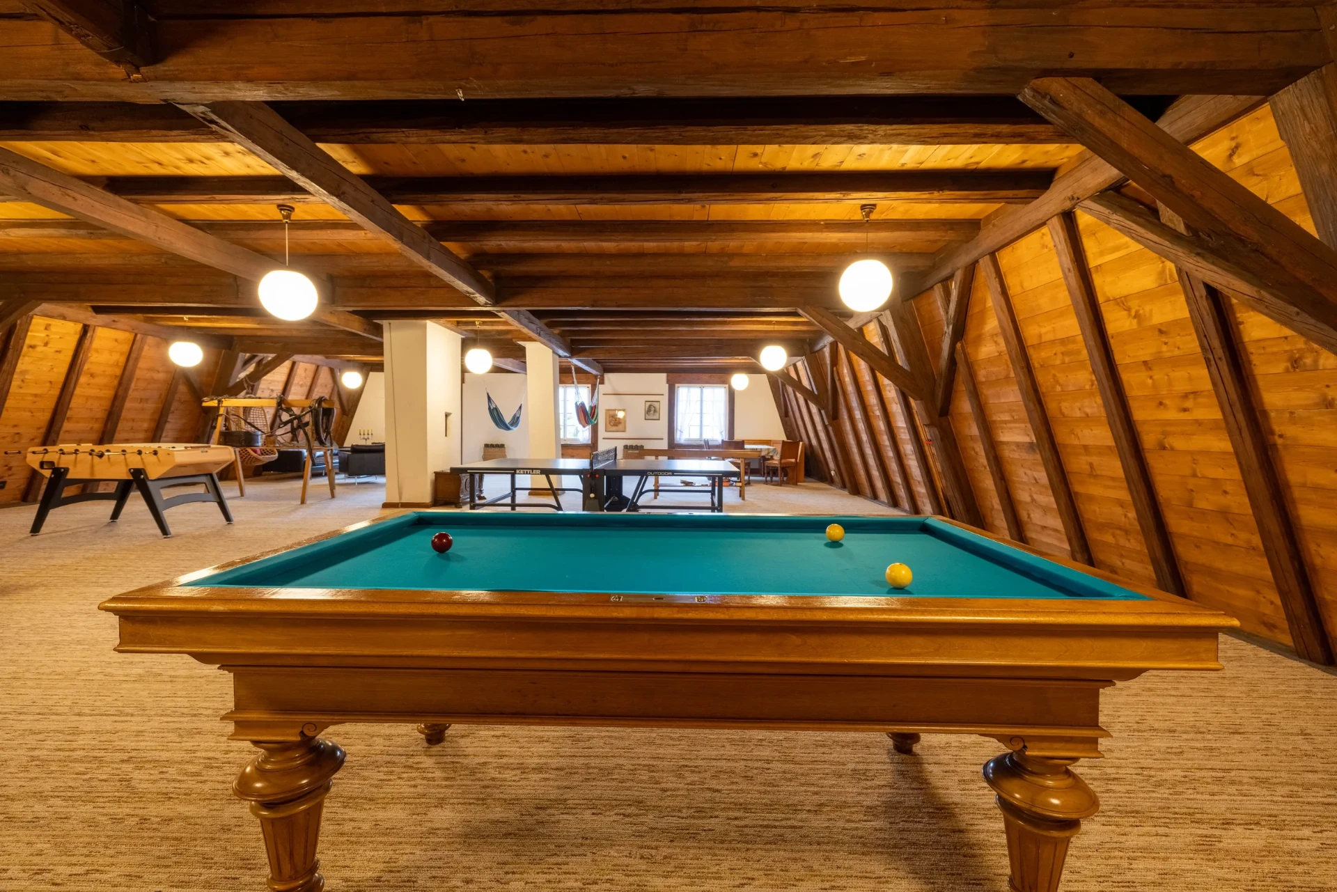Billardtisch unter sichtbaren Holzbalken im Spielezimmer