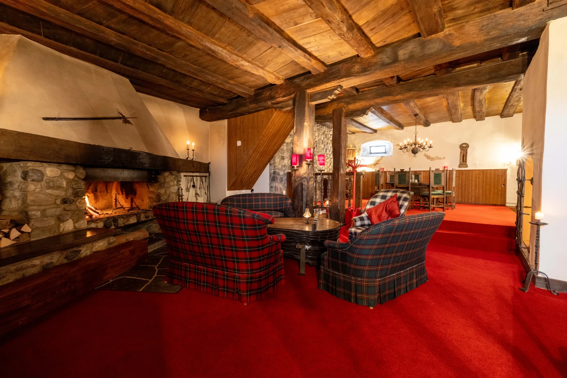 Event-Keller: Cheminée-Lounge mit roten Teppichböden, Sesseln und Blick zum Essbereich